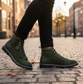 Popps 1961 MOD Mens Suede Monkey Boots in Green, worn with dark trousers on a cobbled street