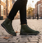 Popps 1961 MOD Mens Suede Monkey Boots in Green, worn with dark trousers on a cobbled street